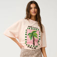 Woman wearing a pink graphic t-shirt with palm tree design and leopard print skirt on a white background
