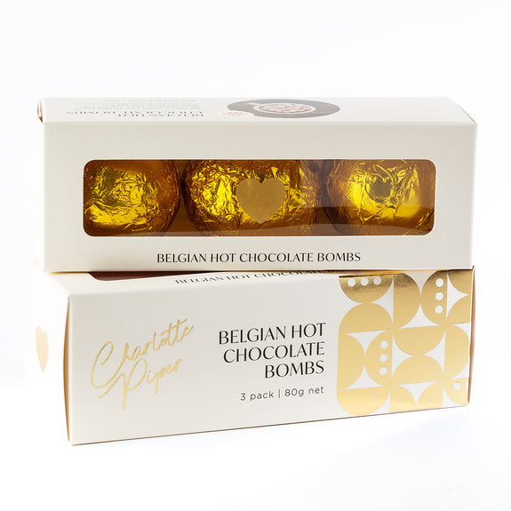 Box of Belgian Hot Chocolate Bombs with gold packaging on a white background