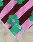 Towel with pink and brown stripes and green floral designs on a beige surface