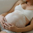 Pregnant woman holding her belly with a neutral background