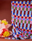 Colorful quilted picnic rug with a patchwork pattern on a brown background