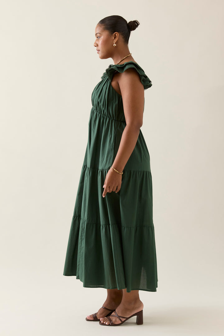 Woman wearing a green isle of mine dress against a plain background