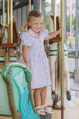 Young girl in a striped dress standing on a carousel