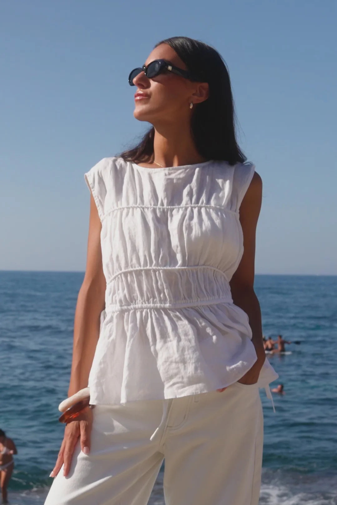 Woman in a white outfit standing by the ocean