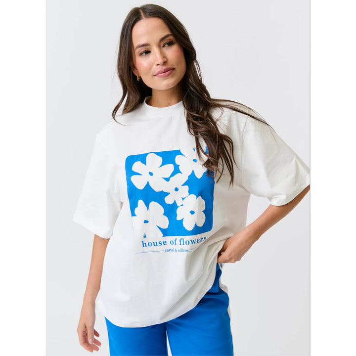 Woman wearing a white t-shirt with blue floral design and text on a plain background