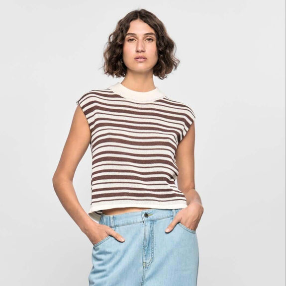 Woman wearing a striped sleeveless top and light blue jeans on a white background