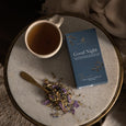 Tea cup, spoon, and 'Good Night' tea box on a textured surface