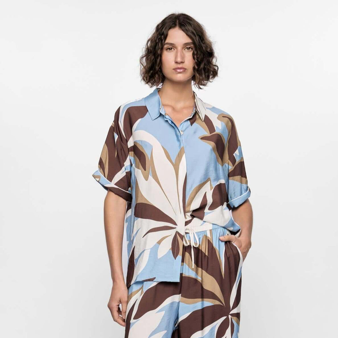 Person wearing a patterned dress with a belt on a white background