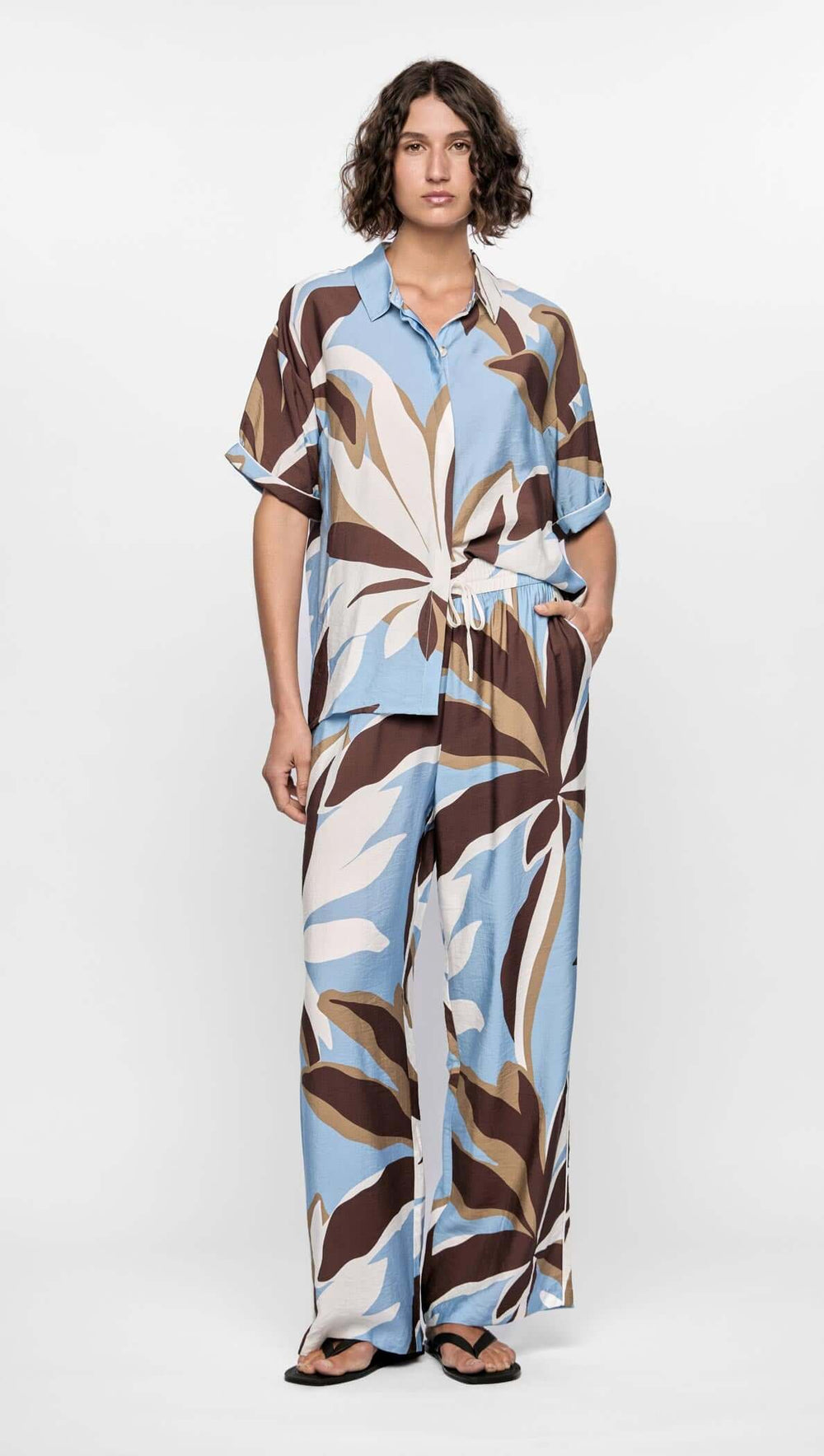 Person wearing a patterned dress with a belt on a white background