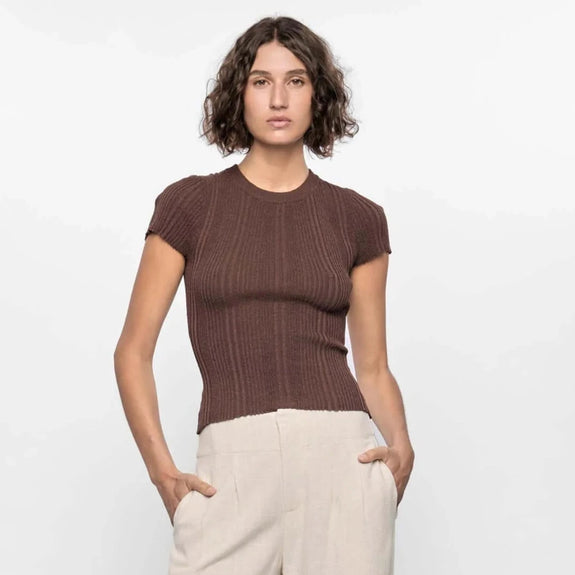Woman wearing a brown ribbed sweater and beige wide-leg pants on a white background