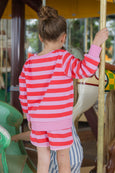 Child in a red and pink striped outfit on a carousel