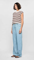 Woman wearing a striped sleeveless top and light blue jeans on a white background