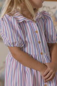 Child wearing a striped dress with a blurred background