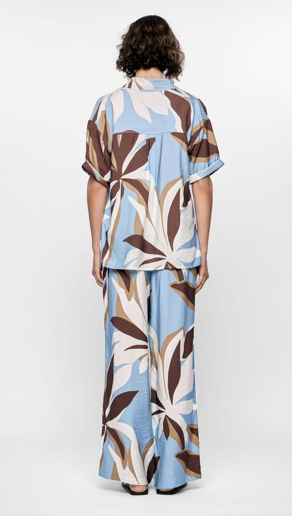 Person wearing a blue and brown patterned outfit on a white background