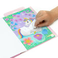 Hand interacting with a colorful unicorn-themed activity book on a white background