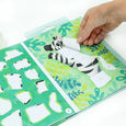 Hand interacting with a children's educational toy featuring a zebra pattern on a green and white background.
