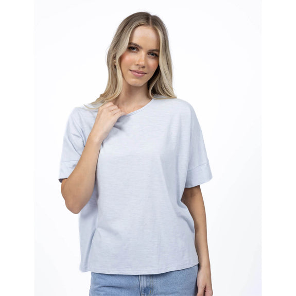 Woman wearing a light gray t-shirt and blue jeans on a white background