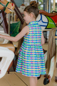 Young girl in a colorful checkered dress on a carousel.