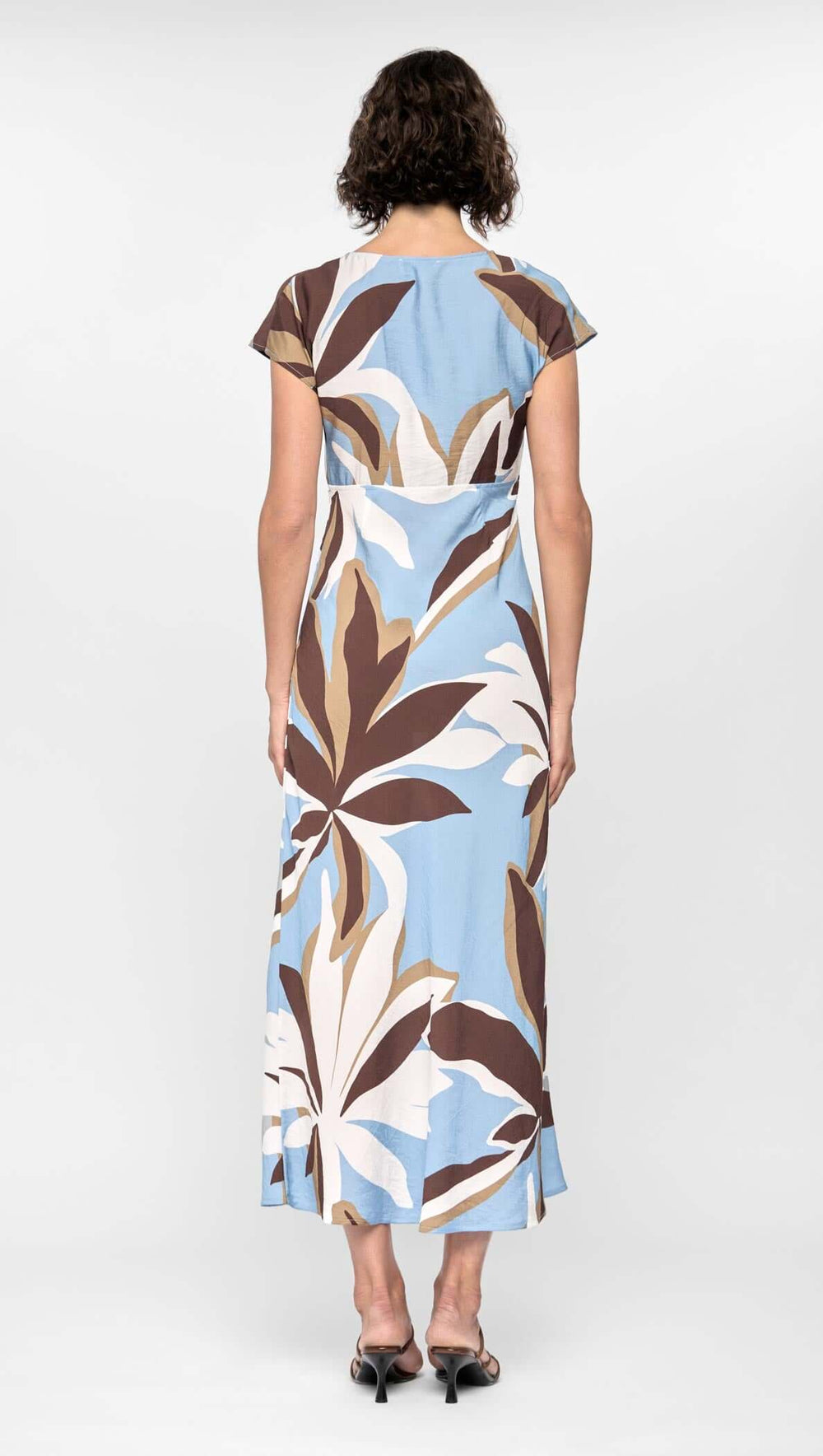 Woman wearing a blue dress with leaf pattern on a white background