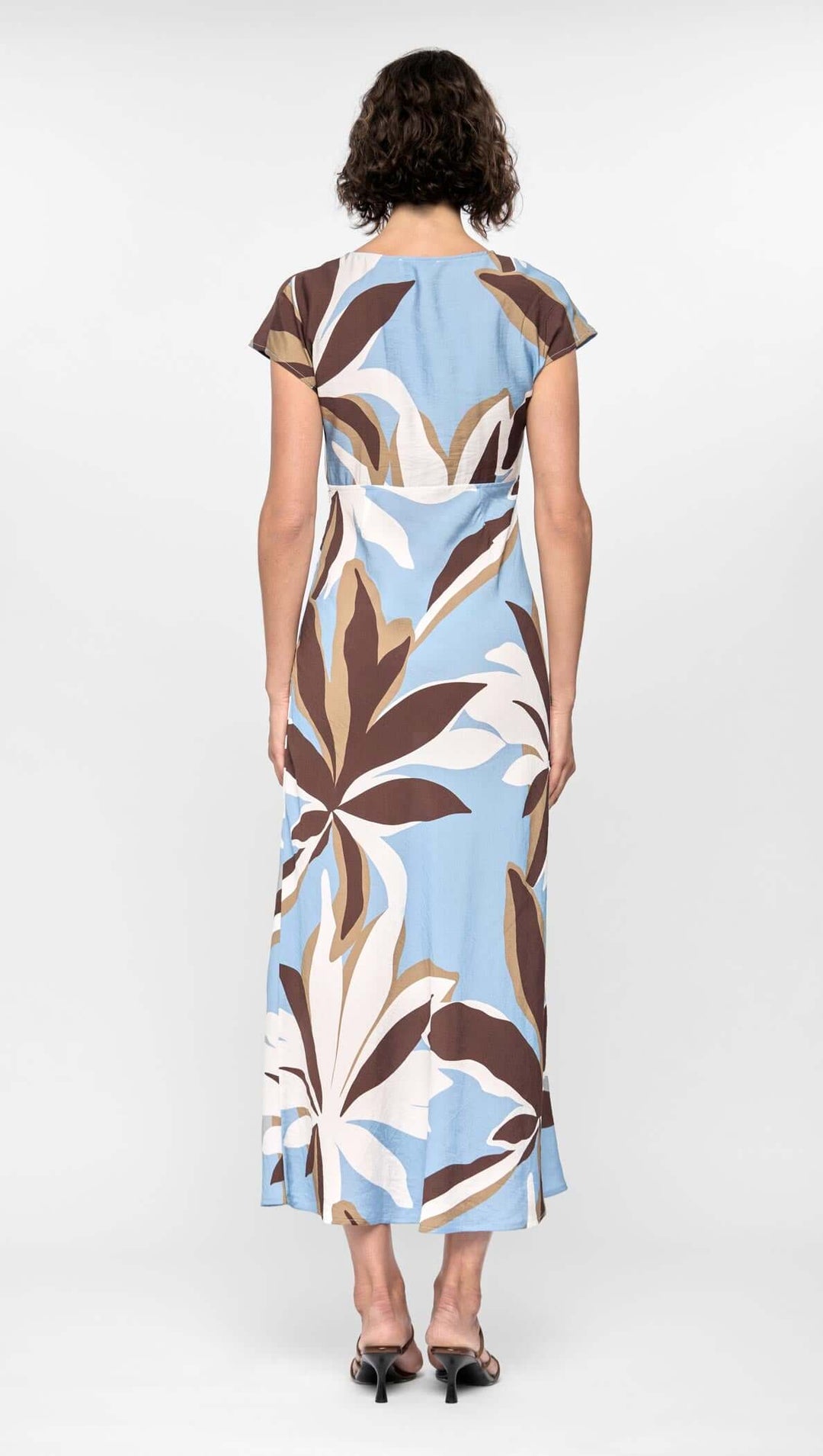 Woman wearing a blue dress with leaf pattern on a white background