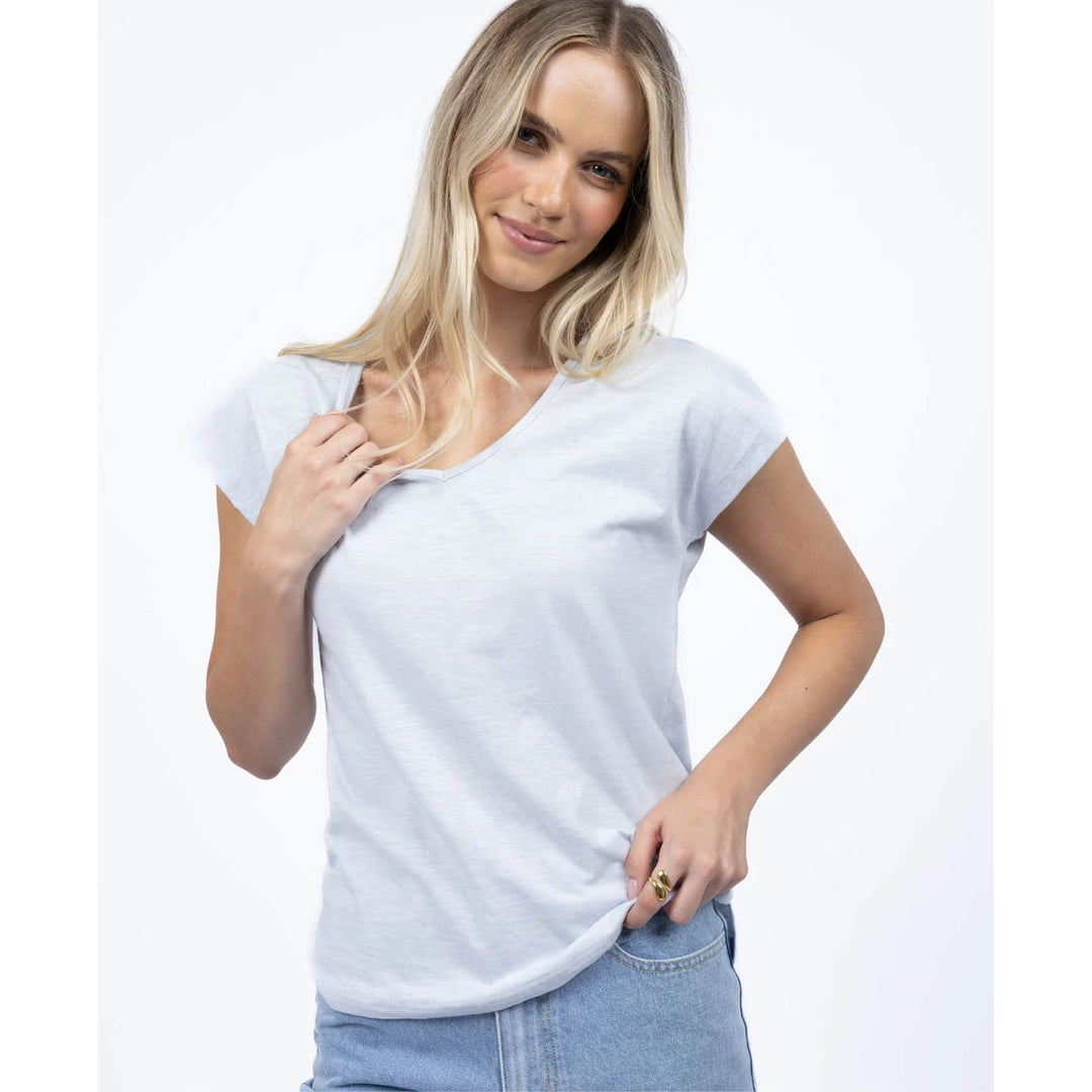 Woman wearing a plain white t-shirt and blue jeans on a light gray background