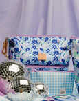 Colorful floral and checkered bags with disco balls on a light purple background