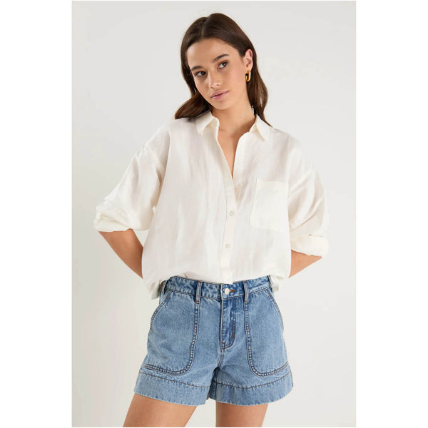 Woman wearing a white shirt and denim shorts on a light gray background