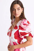 Woman wearing a red and white floral dress on a light gray background