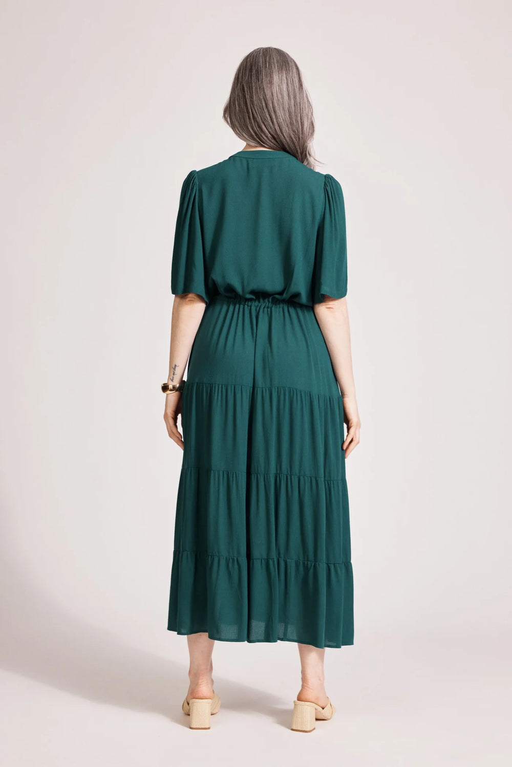 Woman wearing a Eb & Ive green dress with a plain background