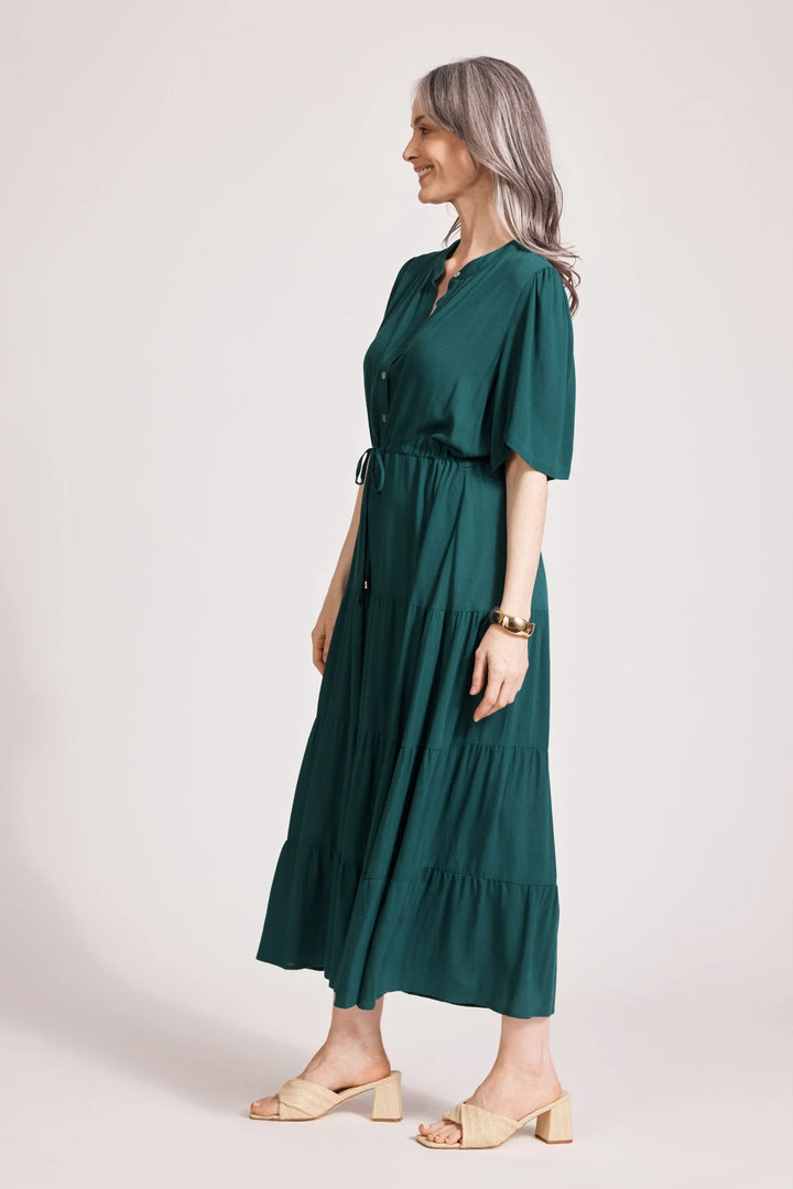 Woman wearing a Eb & Ive green dress on a plain background
