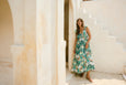 Woman in a floral isle of mine dress standing on a white staircase with columns in the background