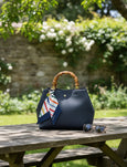 Blue handbag with a bamboo handle on a wooden table outdoors