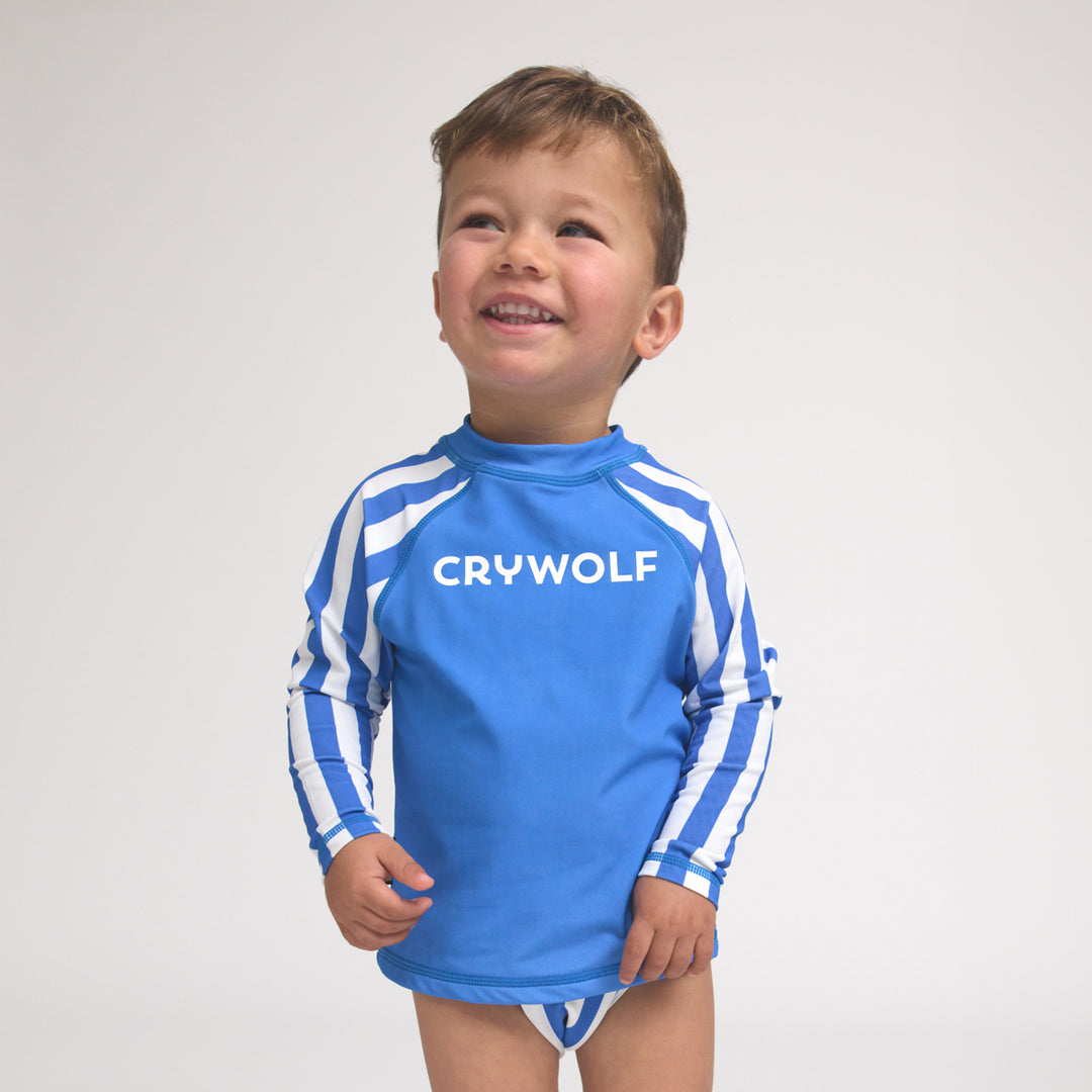 Child wearing a blue and white striped crywolf swimsuit with 'CRYWOLF' branding on a light gray background