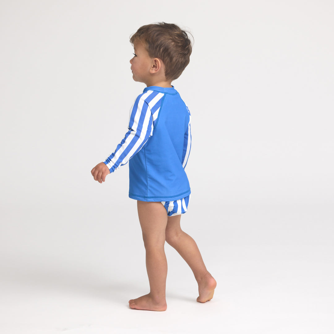 Child wearing crywolf  blue and white striped rash vest and board shorts on a white background