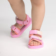 Pink and orange crywolf beach sandals worn by a child on a light gray background