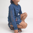 Child wearing a blue long-sleeve rash vest and shorts with 'Crywolf' branding on a white background