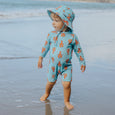Crywolf Child wearing a light blue swimsuit with orange patterns on a beach