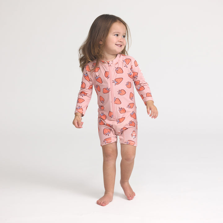 Crywolf Child wearing a pink onesie with strawberry pattern on a white background