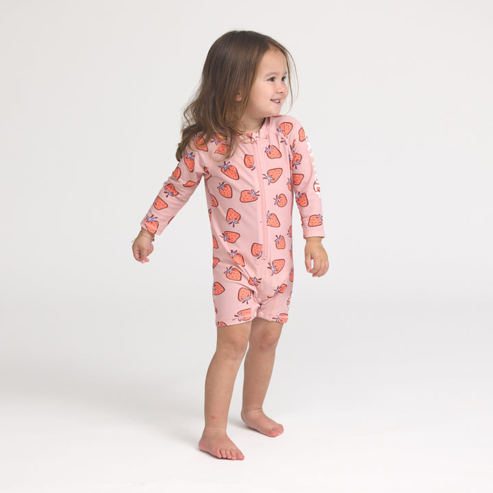 Crywolf Child wearing a pink strawberry-patterned onesie on a white background
