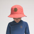 Child wearing a pink bucket hat and blue shirt with a brand logo on a light gray background