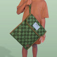 Person holding a green checkered bag with a visible brand label against a light green background