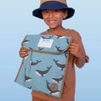 Child holding a blue bag with whale pattern against a light blue background