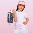 Child holding a small bag with a cherry design on a pink background