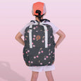 Person wearing a backpack with cherry pattern on a pink background