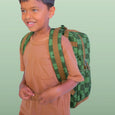 Child wearing a green checkered backpack against a light green background