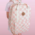 Person wearing a pink and white checkered backpack with a visible brand logo on a pink background