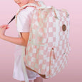 Person wearing a pink and white checkered backpack against a pink background