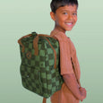 Child wearing a green checkered backpack against a light green background