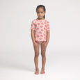 Young girl wearing a crywolf pink rash set with strawberry pattern on a white background