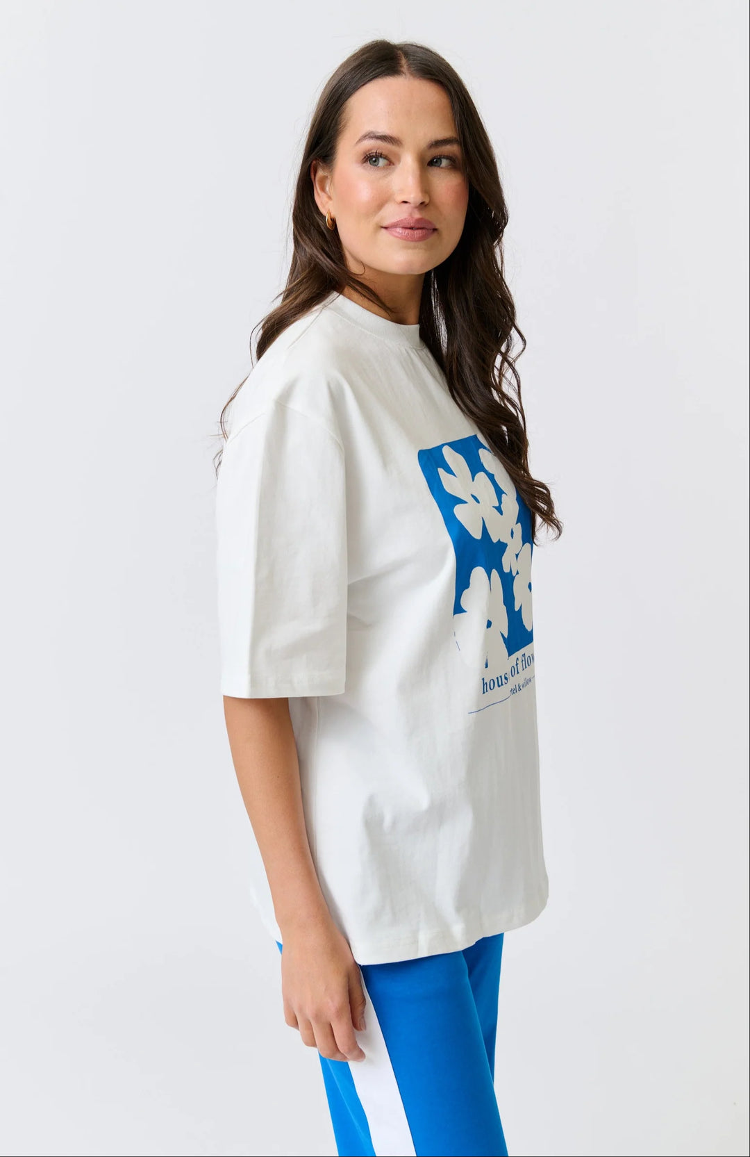 Woman wearing a white oversized t-shirt with a blue graphic design on a light gray background